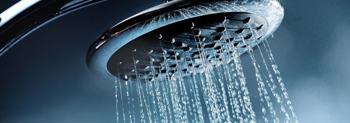 Close-up of a modern shower head with water streaming down.